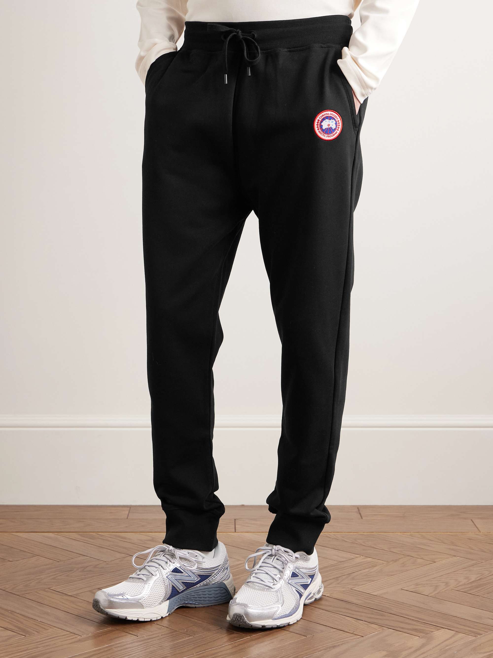 CANADA GOOSE بنطال Huron الرياضي من قطن جيرسي مزين بشعار العلامة بتطريز نافر بقصّة تضيق تدريجياً