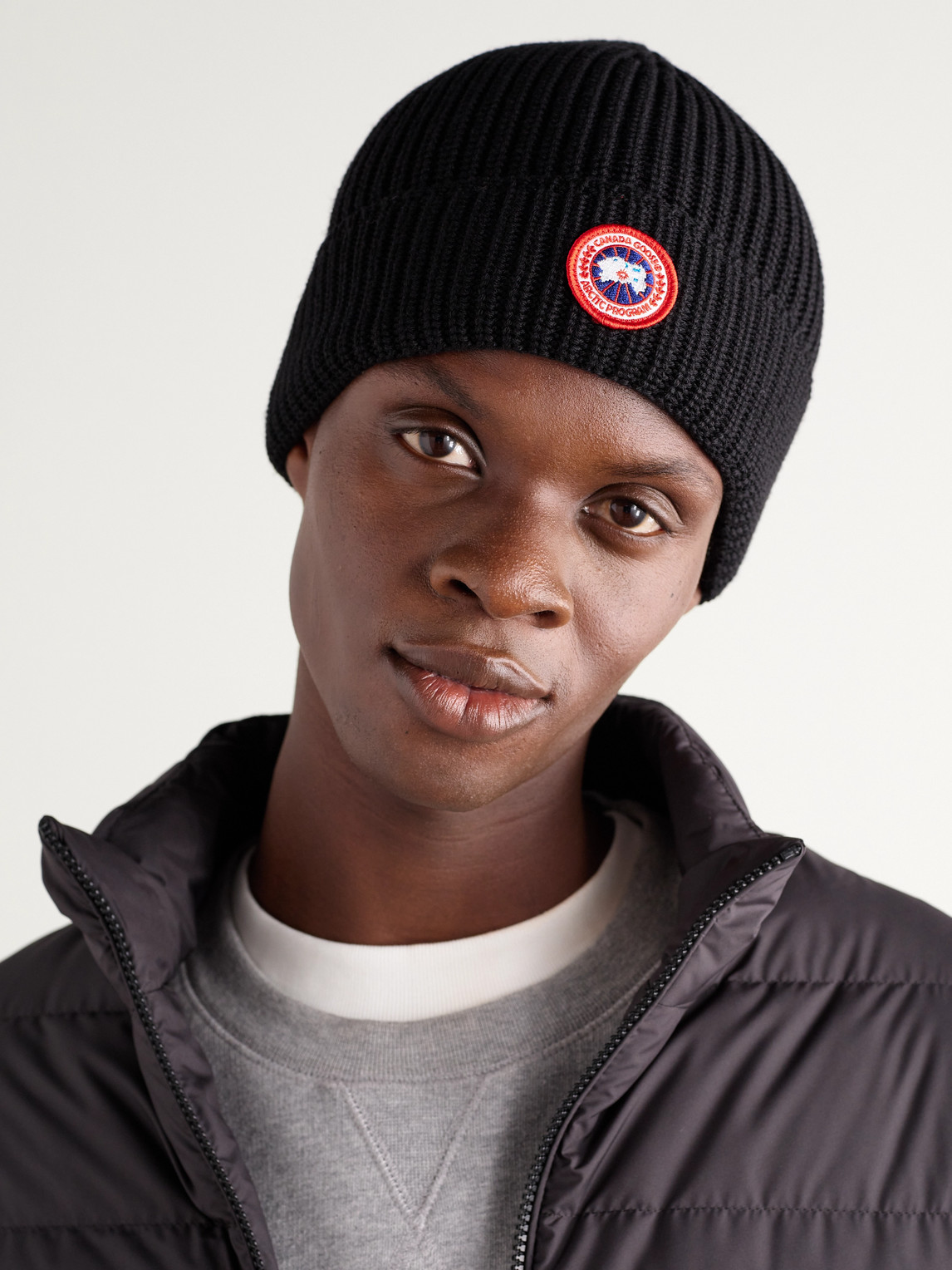 Shop Canada Goose Logo-appliquéd Ribbed Merino Wool Beanie In Black